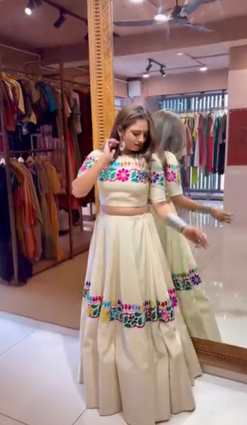 Woman trying on a traditional outfit with colorful patterns in a clothing store.