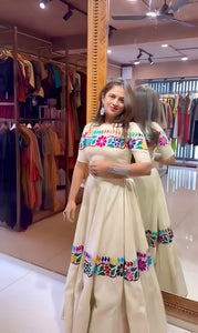Woman wearing a colorful embroidered dress in a clothing store.